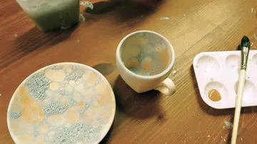 Painted cup and plate with bubbles, table.