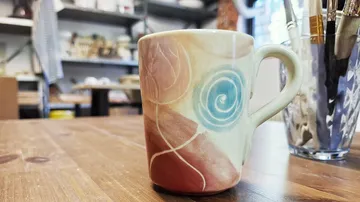 Decorative mug on wooden table in studio.