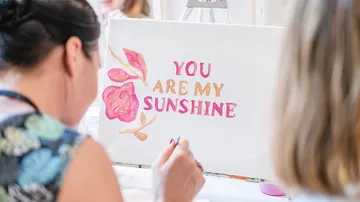 Woman painting canvas with motivational quote.