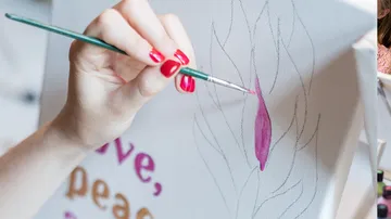 Hand painting canvas with pink brush strokes.