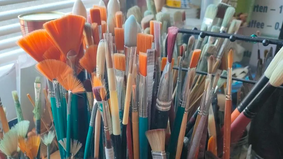 Various paintbrushes in a holder near window.