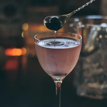 Cocktail with cherry being added, bar setting.