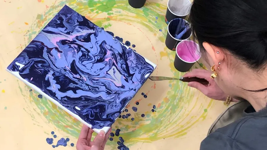 Person painting abstract art with fluid technique.