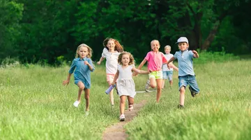 Children running on a grassy path outdoors.