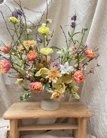 Lebhaftes Blumenarrangement auf Holzstuhl.