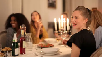 Menschen genießen Abendessen mit Wein und Kerzen.
