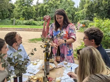 Frau schenkt Wein in einem Gartenabend-Event mit Freunden.