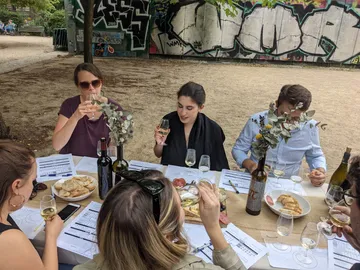 Tisch mit Wein und Snacks, Gruppe feiert im Freien.