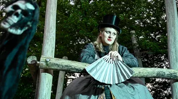 Person in costume holding fan outdoors.