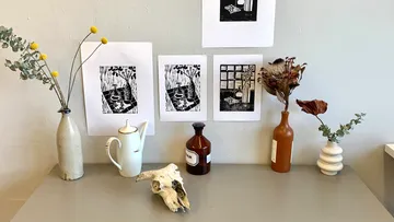 Kunstdrucke über Tisch mit Vasen und Schädel.