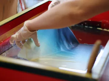 Hand touches paint in water container, shows creative process