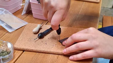 Hands using a drill on a wooden table.