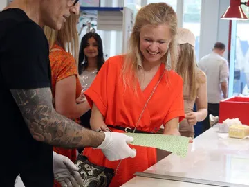 Woman smiles while someone hands a green object.