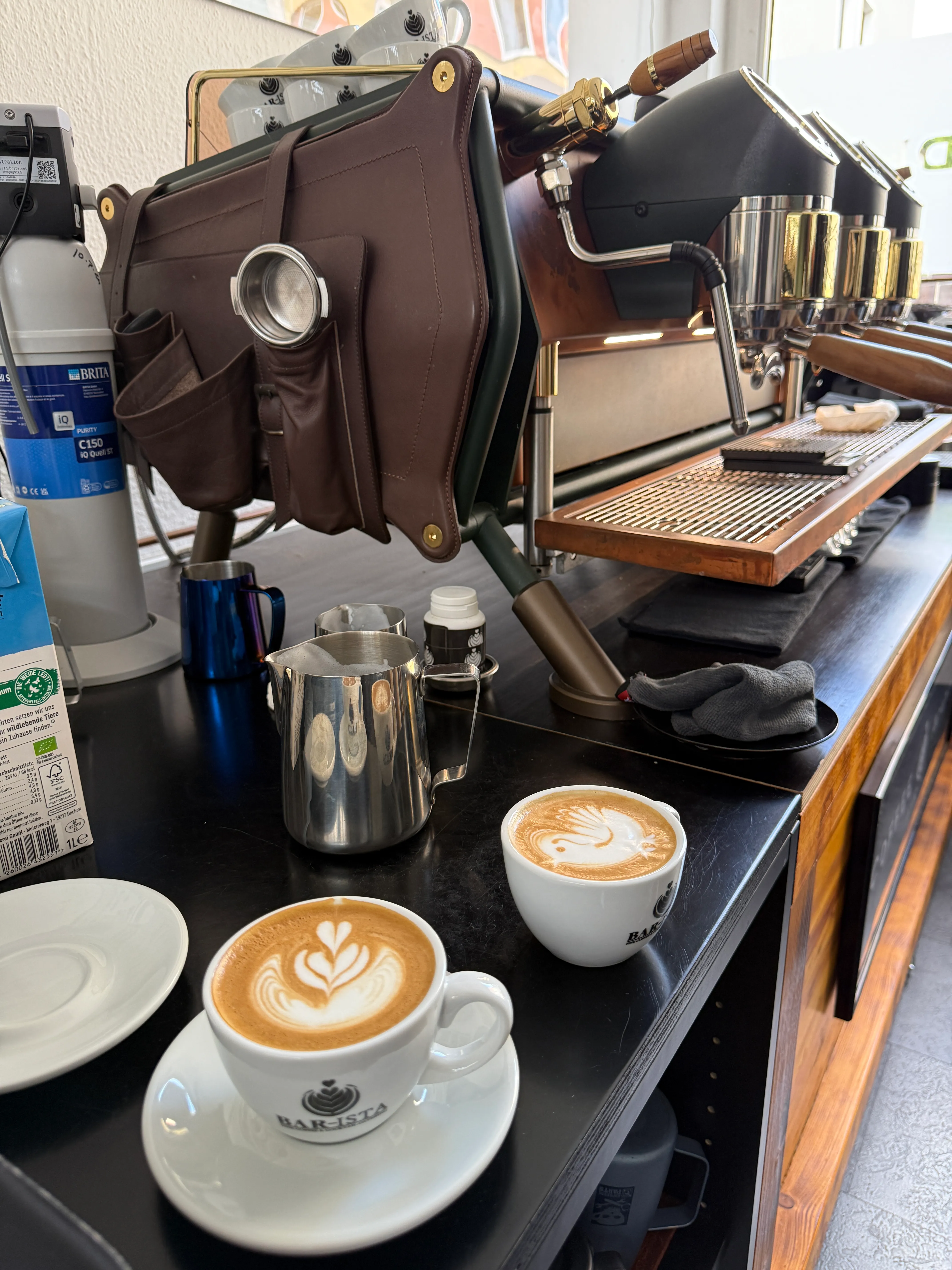 Espressomaschine neben Tassen mit Latte Art.