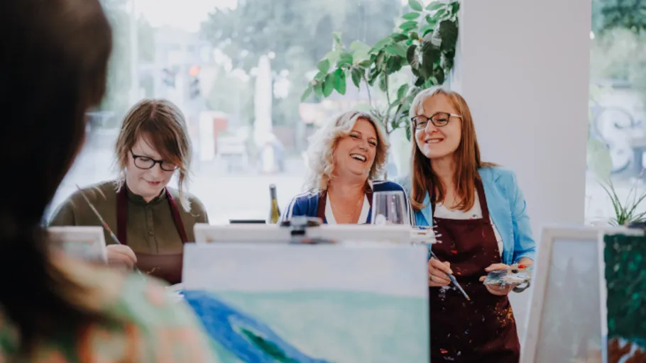Three women enjoying painting indoors.
