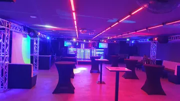 Leerer Nachtclub mit bunten Lichtern und Tischen.