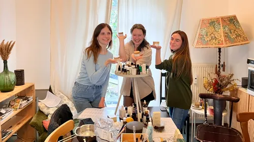 Drei Frauen lächeln mit Kosmetikprodukten in der Nähe.