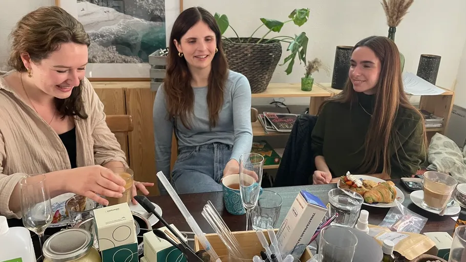 Drei Frauen lächeln, trinken Kaffee drinnen.