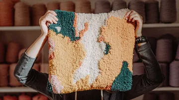 Person holding colorful woven textile in yarn store.
