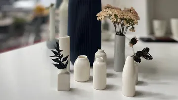 Keramikvasen mit Trockenblumen auf Tisch.
