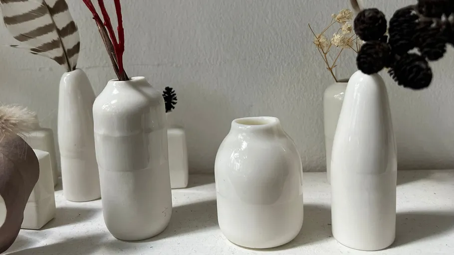 White ceramic vases with dried plants inside.