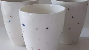 Drei weiße Tassen mit bunten Punkten.