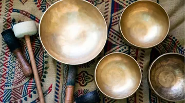 Goldene Klangschalen und Schlägel auf gemustertem Stoff.