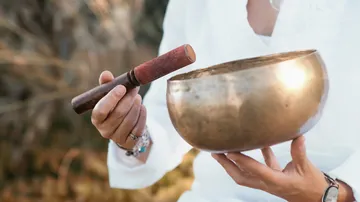 Person holding singing bowl outdoors.