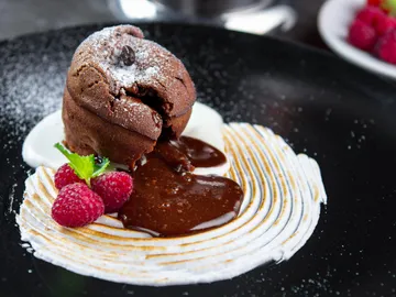 Chocolate cake drips surrounded by cream and berries.