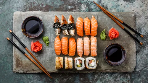 Assortiertes Sushi auf Steinplatte angeordnet.