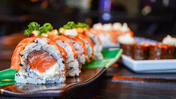Sushirollen mit Lachs und Garnierung auf Teller.
