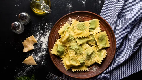 Ravioli auf Teller mit Käse und Öl.