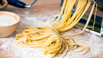 Fresh pasta being rolled from machine.