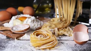 Hausgemachte Pasta, Eier und Mehl auf Holztisch.