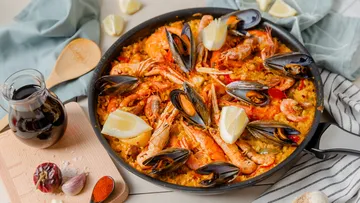 Paella with seafood in a pan, lemon wedges.