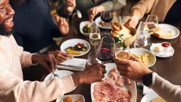People raising glasses at dinner table.