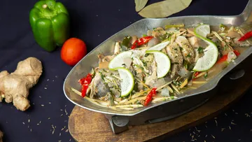 Fisch mit Limettenscheiben in Metallschale.
