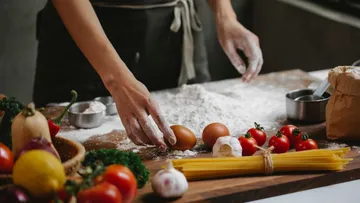 Person preparing pasta with eggs and vegetables.