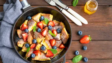 Kaiserschmarrn mit Beeren in einer Pfanne auf Tisch.