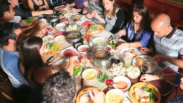 Gruppe isst Fondue an einem großen Tisch.
