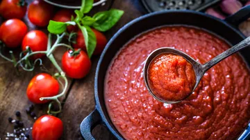 Tomato sauce in ladle over skillet.