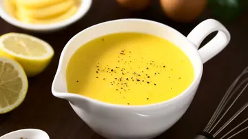 Gelbe Soße mit Pfeffer in weißer Schüssel.