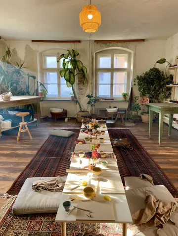Sonniger Raum, Tisch mit Kunstbedarf, üppige Pflanzen.