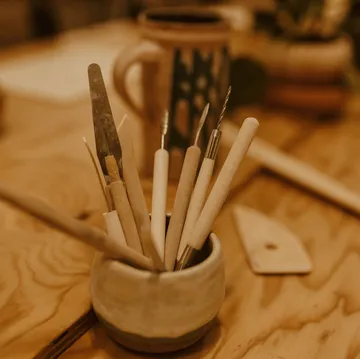Sculpting tools in ceramic holder on table.