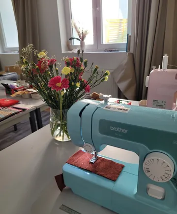 Nähmaschine und Blumen in einem hellen Raum.
