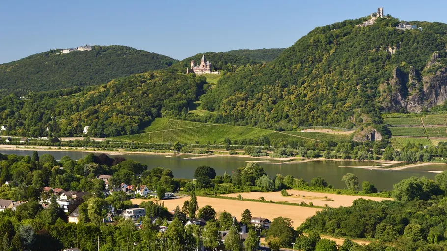 Schloss auf Hügel über Fluss und Dorf.