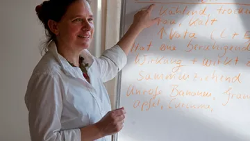 Person pointing at text on whiteboard indoors.