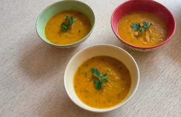 Three bowls of soup with parsley garnish.