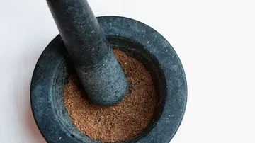 Mortar and pestle grinding spices indoors.