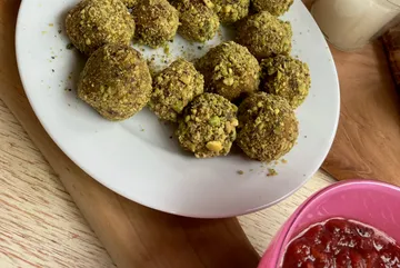Pistazienkugeln auf weißem Teller, Holztisch.